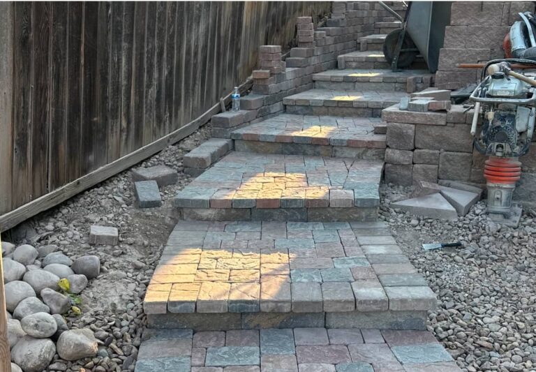 Stone steps under construction, surrounded by rocks and construction tools, with unfinished retaining walls on the side.